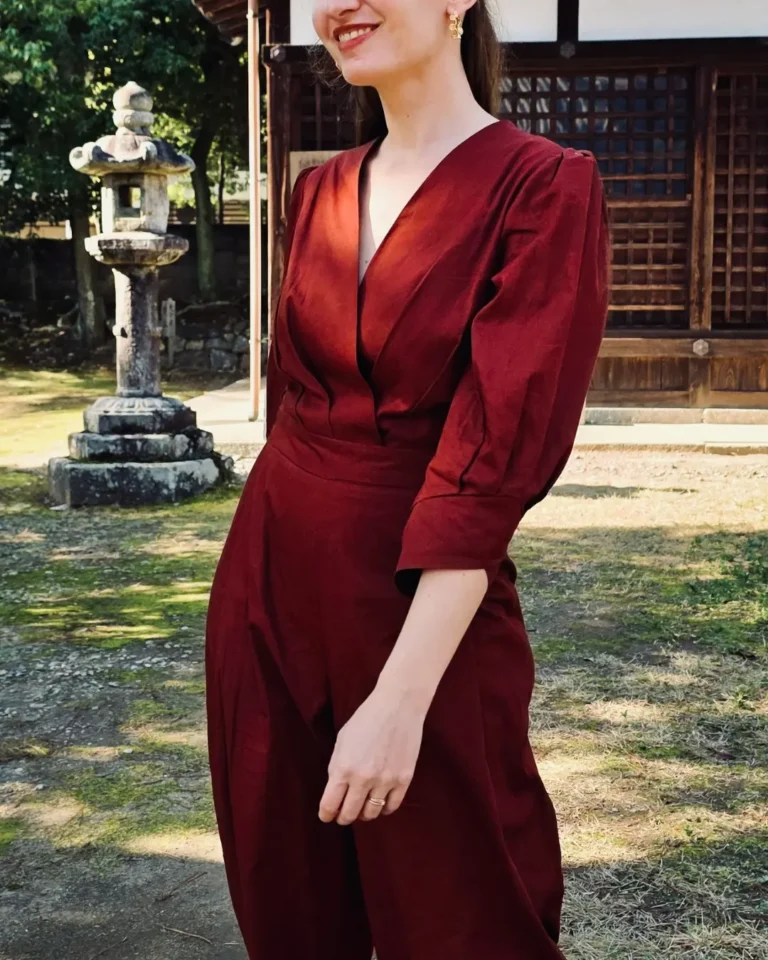 Femme de profil portant la combinaison Martine en tissu rouge brique, haut cache-cœur et pantalon large.